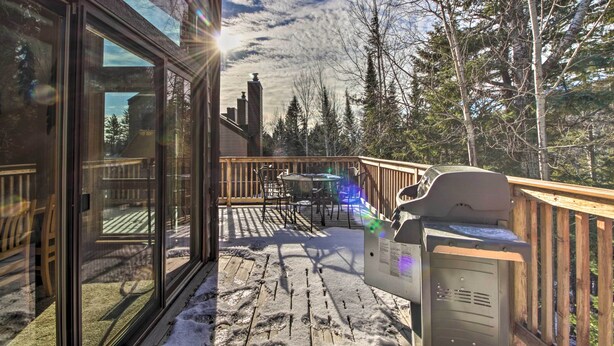 A deck with a grill, a table, and chairs, overlooking a snowy landscape and trees. - Lutsen Mountain Townhome - 2 Mi to Lake Superior! (Lutsen)