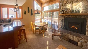 A cozy interior with a stone fireplace, wooden dining table, and chairs. - Lutsen Mountain Townhome - 2 Mi to Lake Superior! (Lutsen)