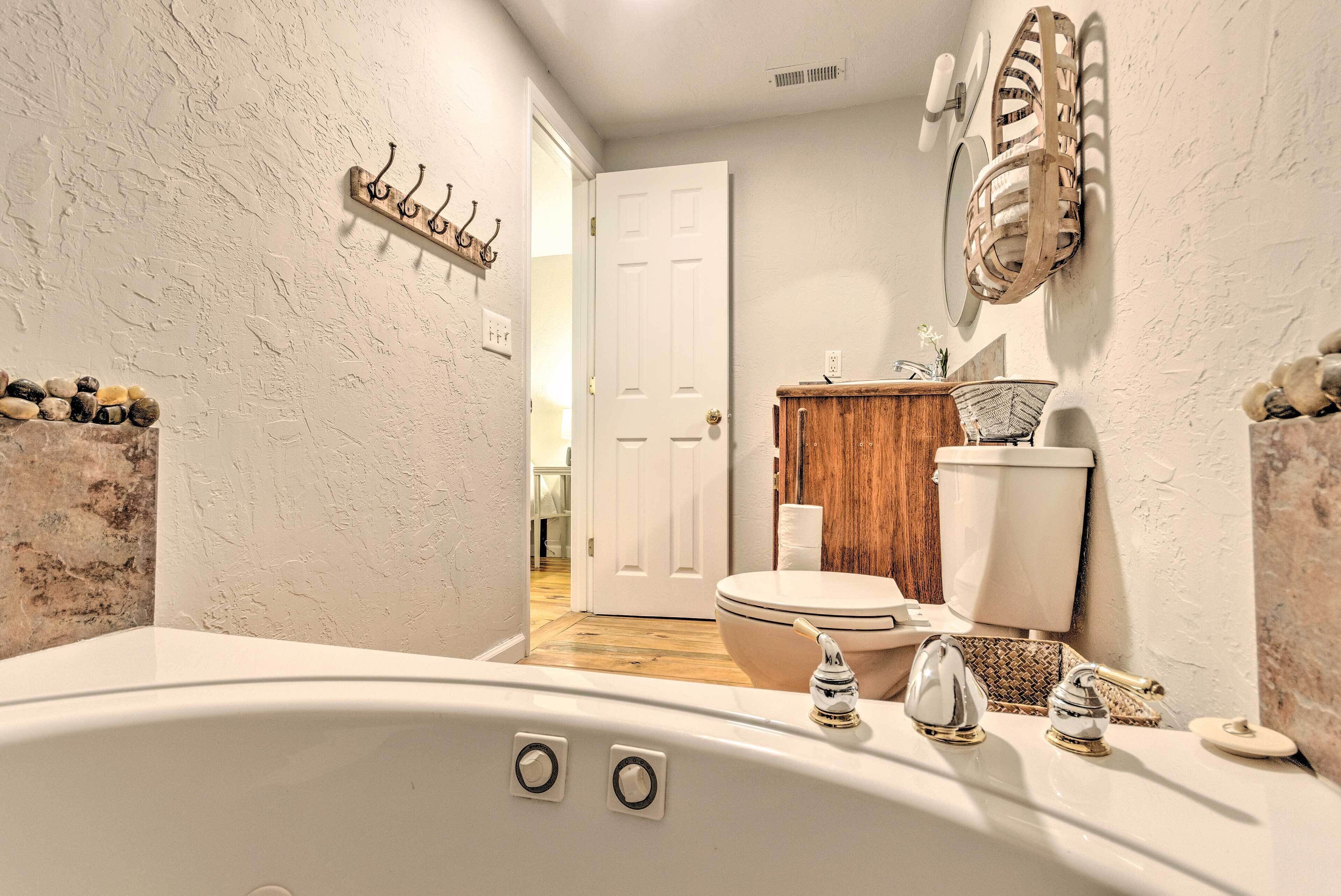A bathroom with a bathtub, toilet, and sink. There is a wooden cabinet and a basket on the wall.