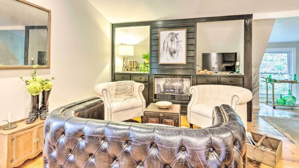 Ein Wohnzimmer mit Kamin, zwei Sesseln, einer Couch und einem Couchtisch.