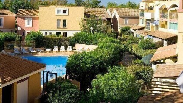 Un complexe hôtelier doté d’une piscine, entouré d’une végétation luxuriante et de bâtiments de style méditerranéen.