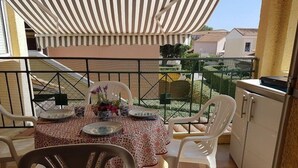 Un balcon avec une table dressée pour le dîner, entouré de chaises, et une vue sur le quartier.