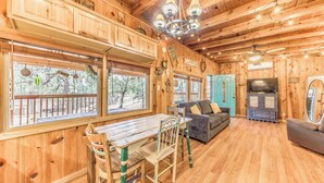 Un interior de madera con una mesa de comedor, sillas, un sofá y un televisor.