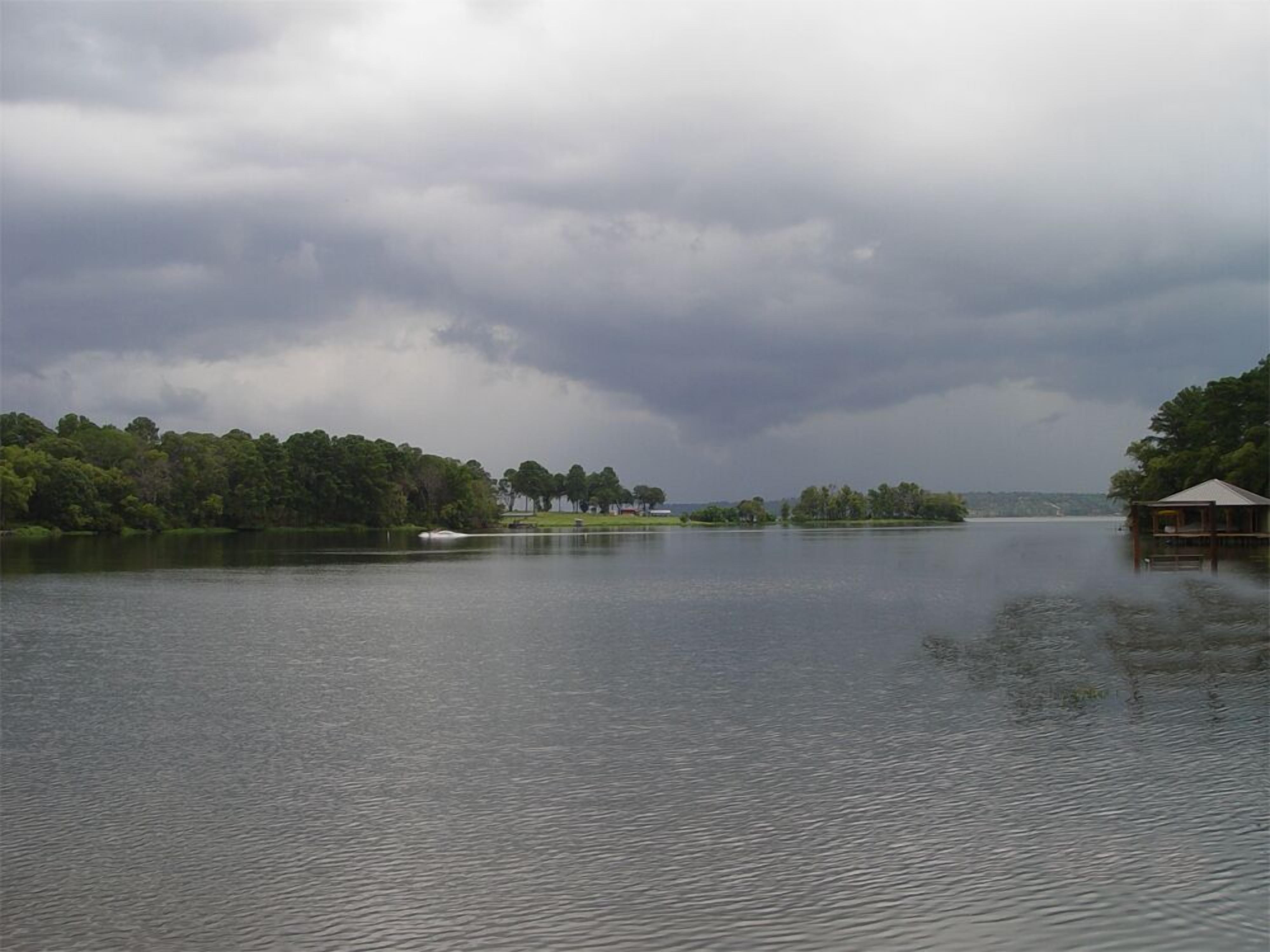 A calm lake with a wooden dock and a small building on the right.