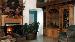 Una sala de estar acogedora con chimenea, muebles de madera y un mueble grande con puertas de cristal.