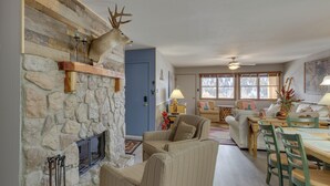 Ein gemütliches Wohnzimmer mit Kamin aus Stein, einem an der Wand befestigten Hirschgeweih und einem Essbereich mit Tisch und Stühlen.