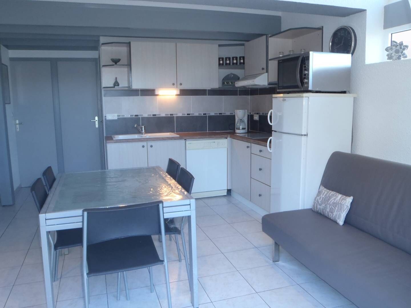Une cuisine compacte comprenant une table à manger, des chaises, un canapé et un four à micro-ondes.