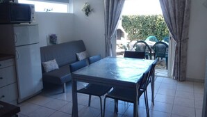 A compact living space with a kitchenette, a dining table, a sofa, and a view of the outside. - VILLA  3 ROOMS MEZ 41m2 + TERRACE 12m2 REF 4027 (MARSEILLAN PLAGE)