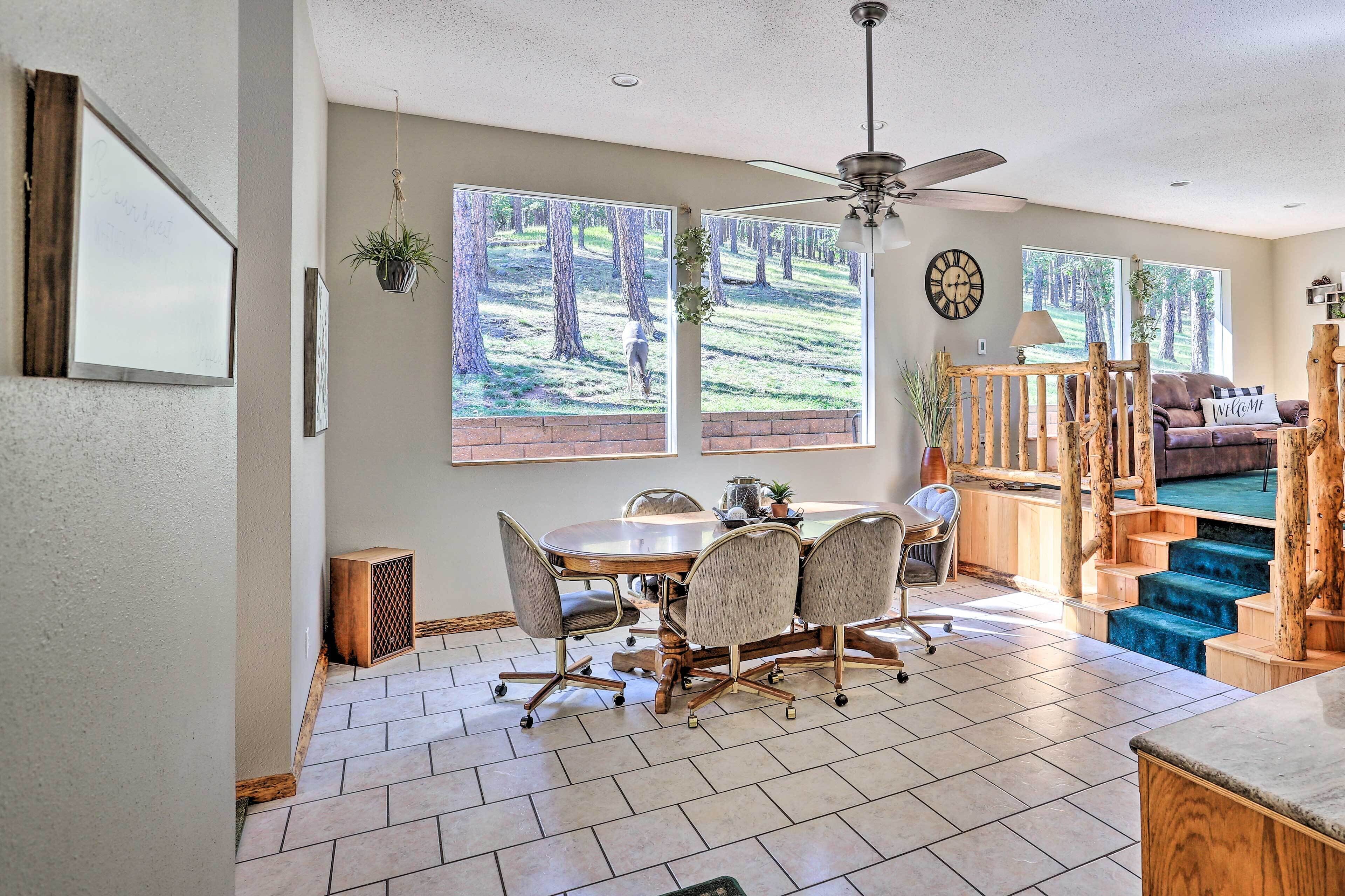 A spacious living area with a dining table, chairs, a sofa, and a staircase with a wooden railing.