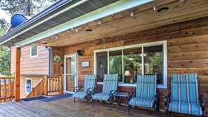 Eine Holzhütte mit Veranda, vier gestreiften Stühlen und einer Holztreppe.