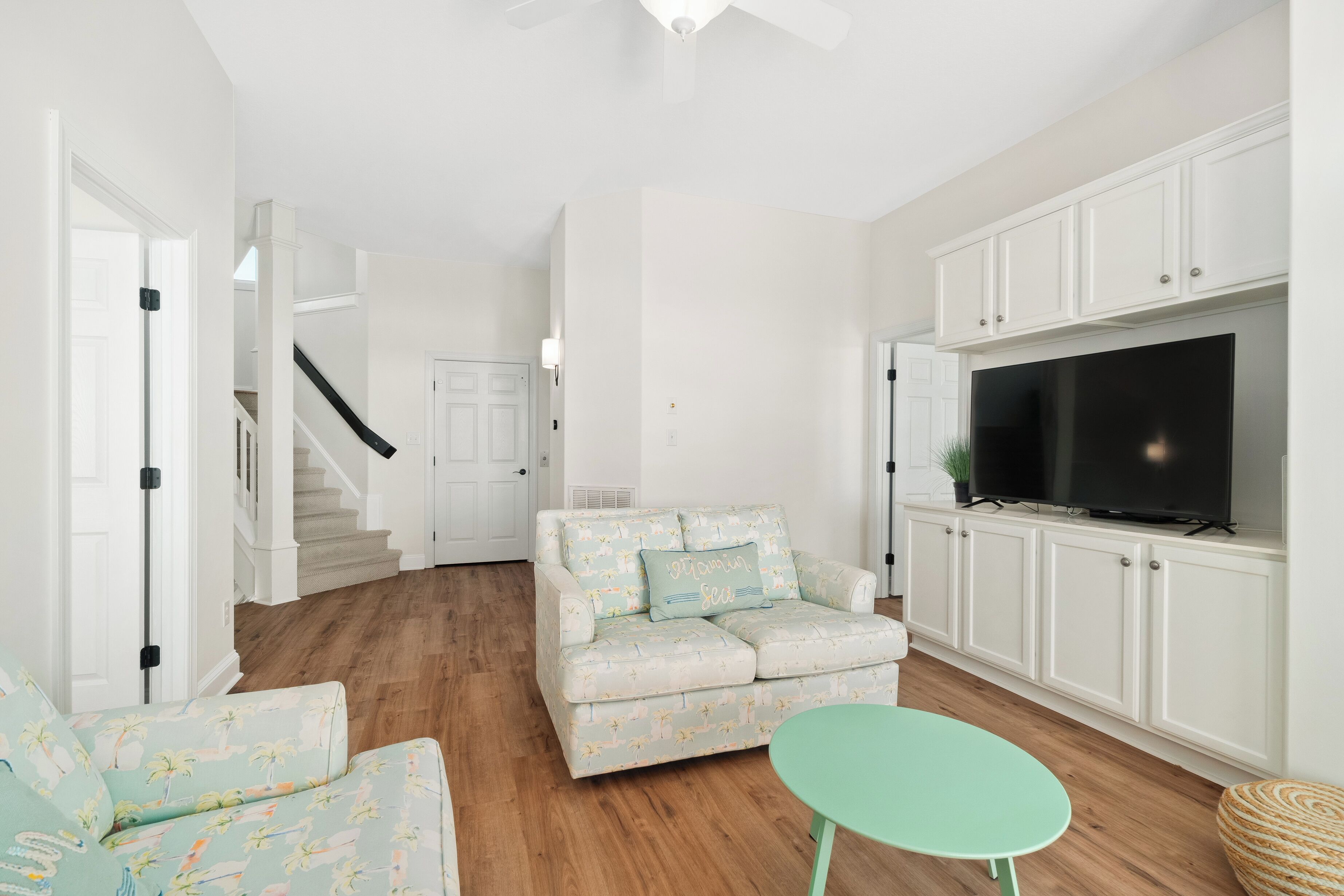 A living room with a sofa, a small table, a TV, and white cabinets.
