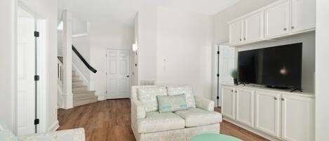 A living room with a sofa, a small table, a TV, and white cabinets.