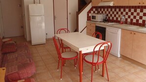 Une cuisine compacte comprenant un coin repas, un réfrigérateur, un four à micro-ondes et un lave-vaisselle.