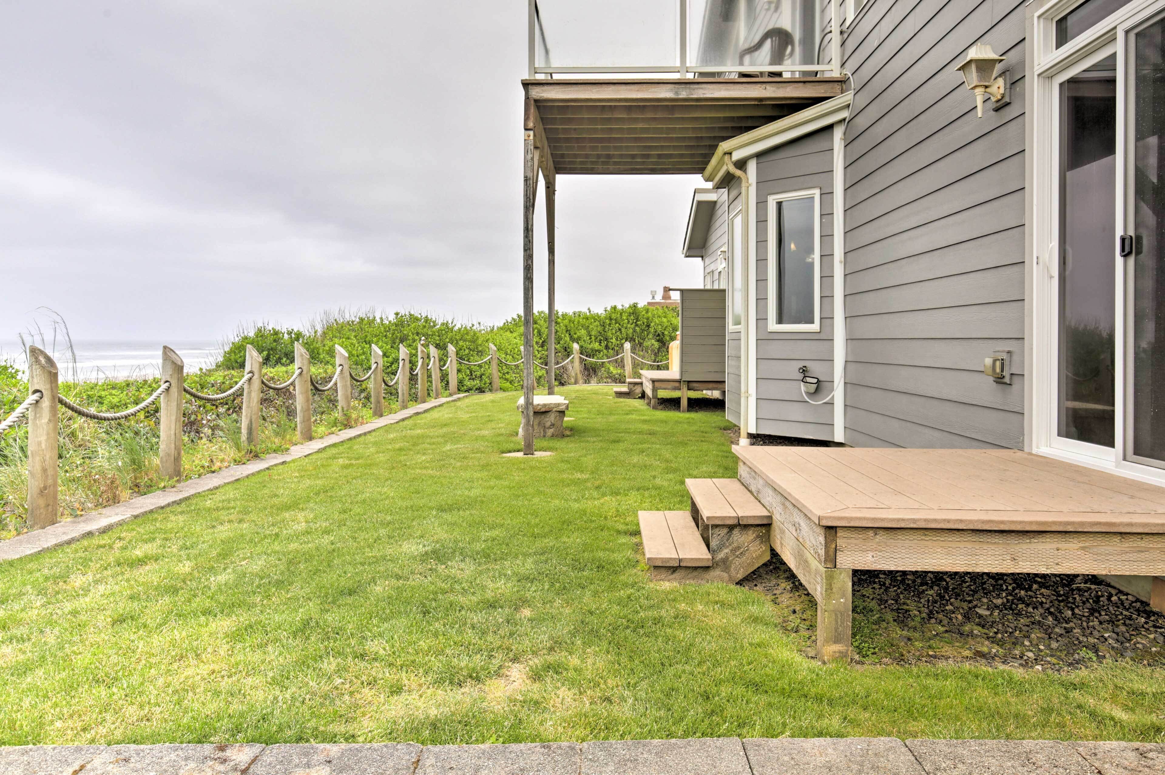A wooden deck with benches, a stone pathway, and a view of the ocean.