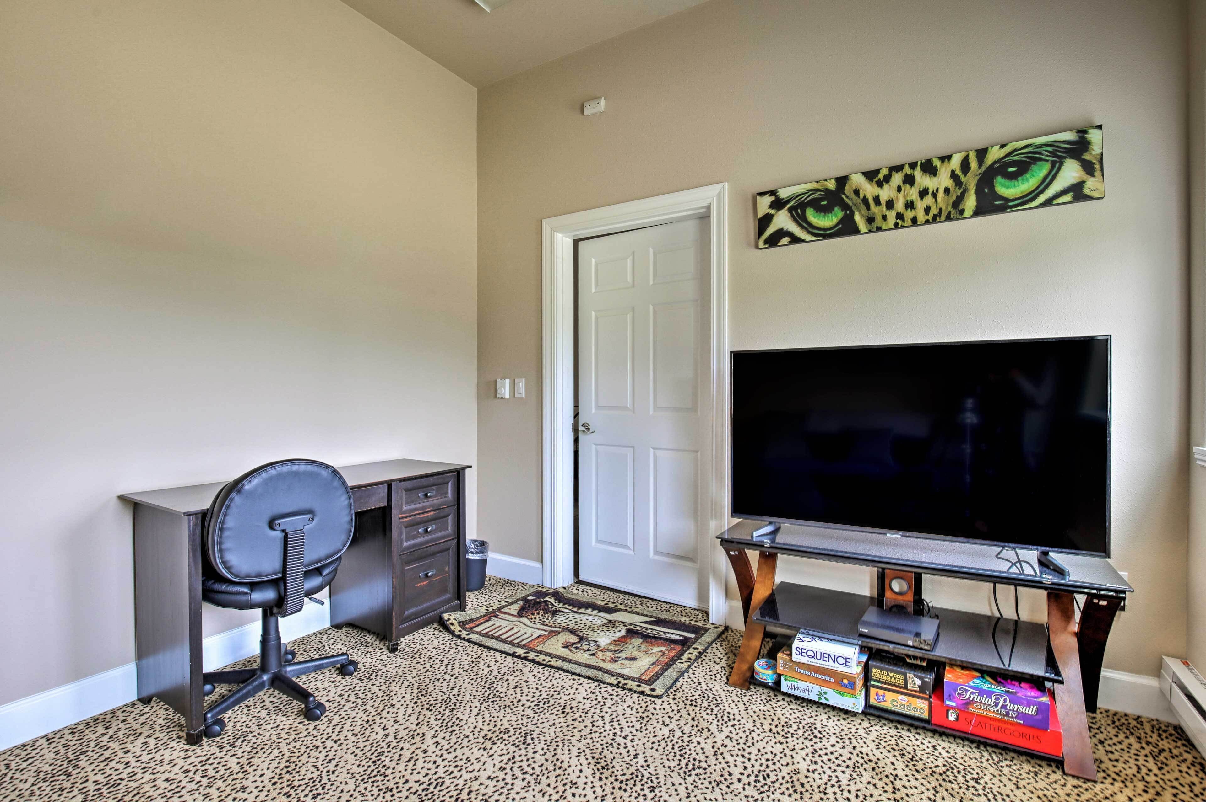 A room with a desk, chair, television, and a door.