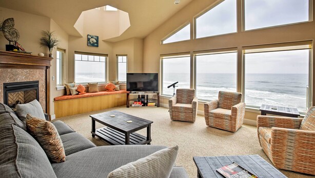 A spacious living room with a large window overlooking the ocean, a fireplace, and comfortable seating. - Oceanfront South Beach Home w/ Hot Tub & Sauna (South Beach)