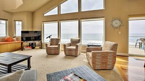 A spacious living room with large windows, a television, comfortable seating, and a view of the ocean. - Oceanfront South Beach Home w/ Hot Tub & Sauna (South Beach)