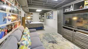 A bedroom with a bed, a sofa, a TV, and a wall with posters. - Decks & Lake Views: Waterfront Hot Springs Home! (Hot Springs)