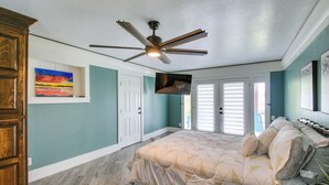 A bedroom with a bed, a ceiling fan, a TV, and a door. - Decks & Lake Views: Waterfront Hot Springs Home! (Hot Springs)