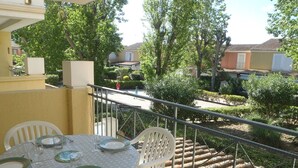 A balcony with a round table set for dining, surrounded by white chairs. - APT 3 ROOMS 36m2 + LOGGIA  7m2 REF 4031 (MARSEILLAN PLAGE)