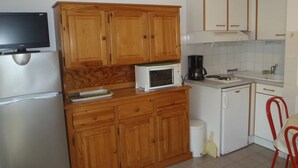 A compact kitchen with wooden cabinets, a microwave, a coffee maker, and a sink. - APT 3 ROOMS 36m2 + LOGGIA  7m2 REF 4031 (MARSEILLAN PLAGE)