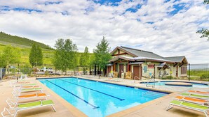 A swimming pool with lounge chairs and a building with a sloped roof. - Ski-in/ski-out Granby Penthouse w/ Mountain Views! (Granby)