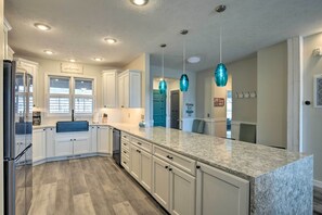 A modern kitchen with white cabinets, a granite countertop, and pendant lighting.