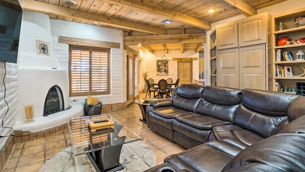 A cozy living room with a leather sofa, fireplace, and wooden ceiling beams. - Las Cruces Home 'La Casa Blanca' w/ Courtyard (Las Cruces)