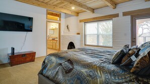 A bedroom with a large bed, a wooden ceiling, a fireplace, and a window. - Las Cruces Home 'La Casa Blanca' w/ Courtyard (Las Cruces)