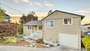 Une maison à deux étages avec un porche à l’avant, un garage et un jardin aménagé.