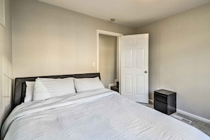 A bedroom with a bed, a nightstand, a door, and a small black cabinet. - Castro Valley Home w/ Bay Area Views! (Castro Valley)
