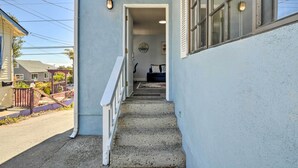 Un escalier étroit menant à une porte, avec une rambarde d’un côté et une fenêtre de l’autre.