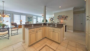 A spacious kitchen with a large island, beige cabinetry, and a decorative backsplash. - Manteo Waterfront Resort Home w/ 30-ft Dock! (Manteo)