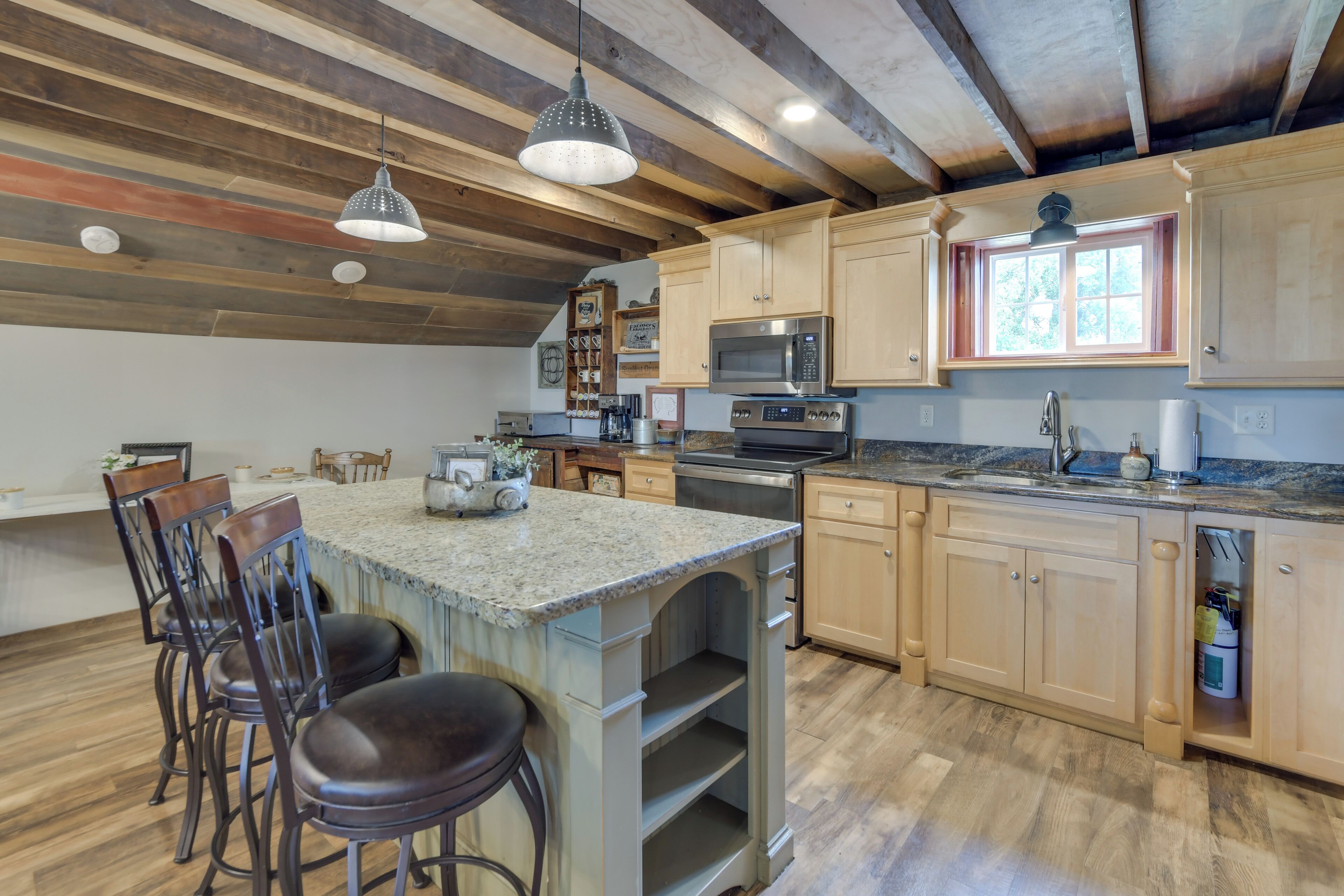 A spacious kitchen with wooden beams, granite countertops, and a large island with bar stools.