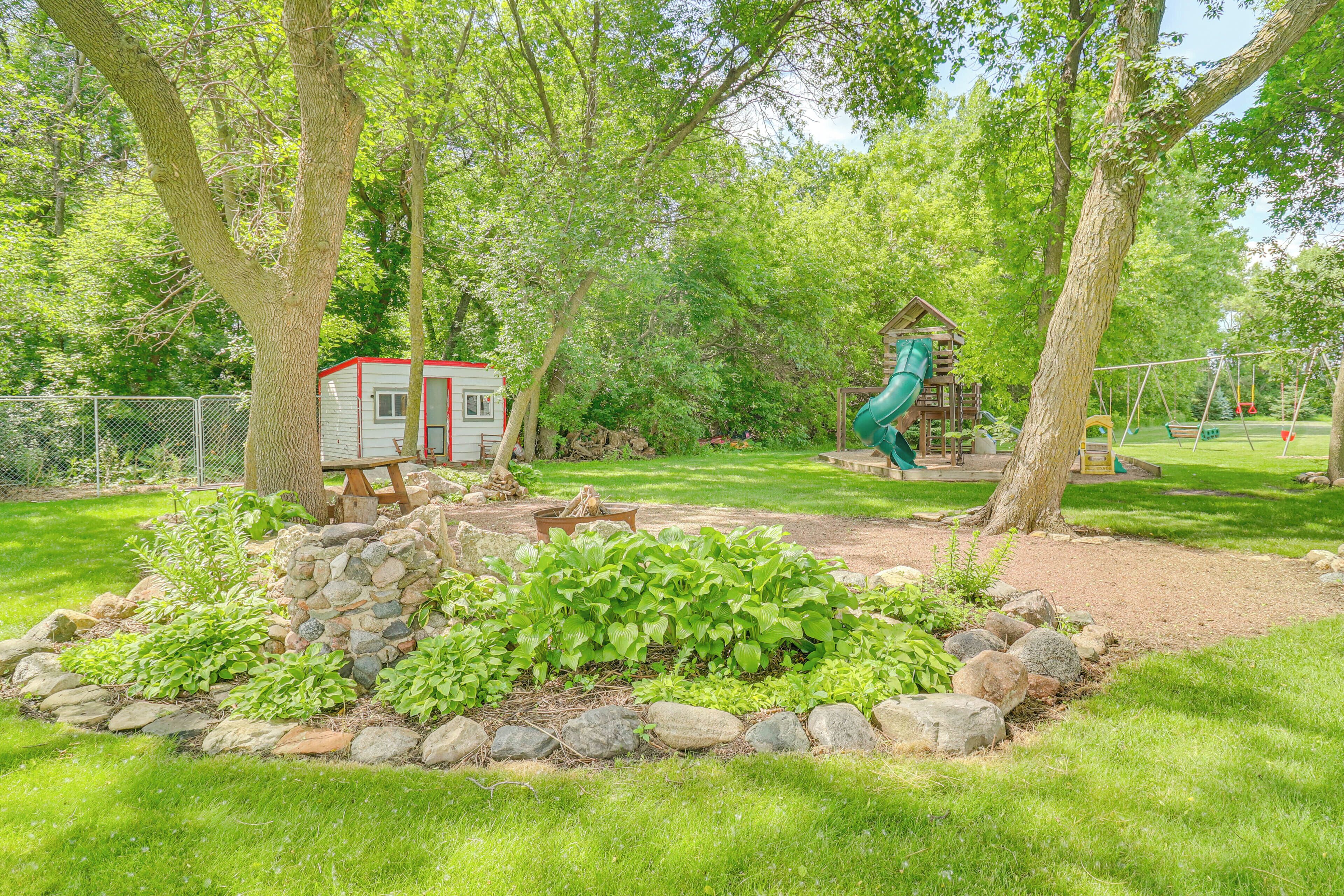 A backyard with a swing set, a playhouse, and a fenced area.