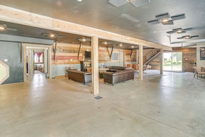 A spacious room with a high ceiling, exposed wooden beams, and a central seating area with leather sofas.
