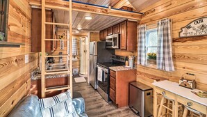 A compact RV kitchen with wooden walls, a kitchenette, a dining area, and a small seating space. - La Petite Maison in Mount Olive w/ Fire Pit! (Mountain View)