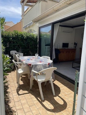 A patio with a table and chairs, a sliding glass door leading to an indoor area with a kitchen counter. - VILLA  3 ROOMS MEZ 48m2 + TERRACE 7m2 REF 4034 (MARSEILLAN PLAGE)