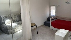 A bedroom with a bed, a sofa, a small table, and a wardrobe. - VILLA  3 ROOMS MEZ 48m2 + TERRACE 7m2 REF 4034 (MARSEILLAN PLAGE)
