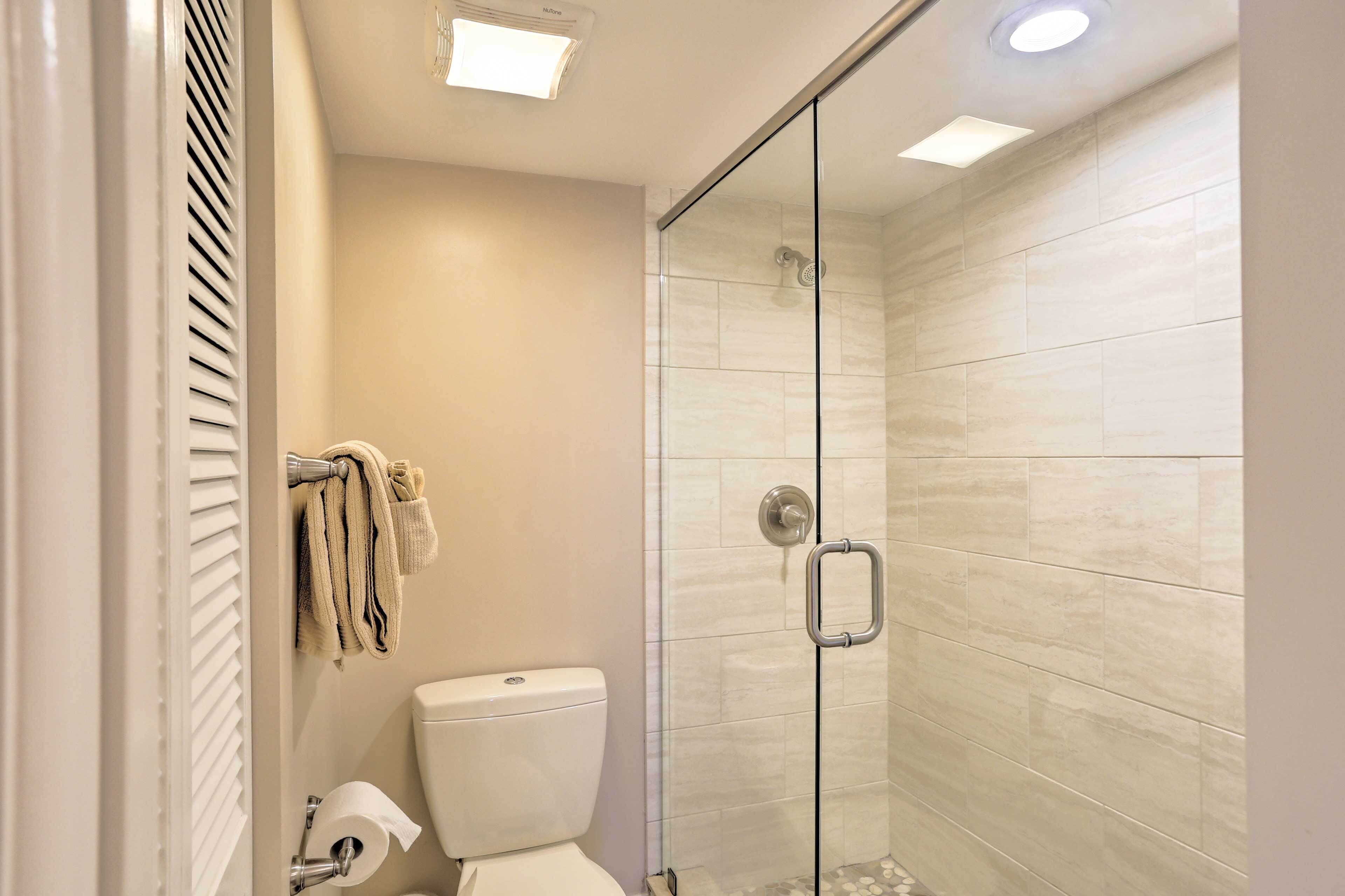 A modern bathroom with a glass shower enclosure, a toilet, and a towel rack.