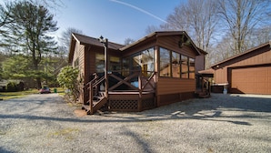 Eine Holzhütte mit Veranda, großen Fenstern und einem Schotterweg.