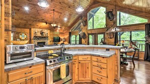A spacious kitchen with wooden cabinets, a large island, and a stone fireplace.