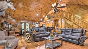A spacious living room with a large leather sofa, wooden flooring, and a staircase leading to an upper level.