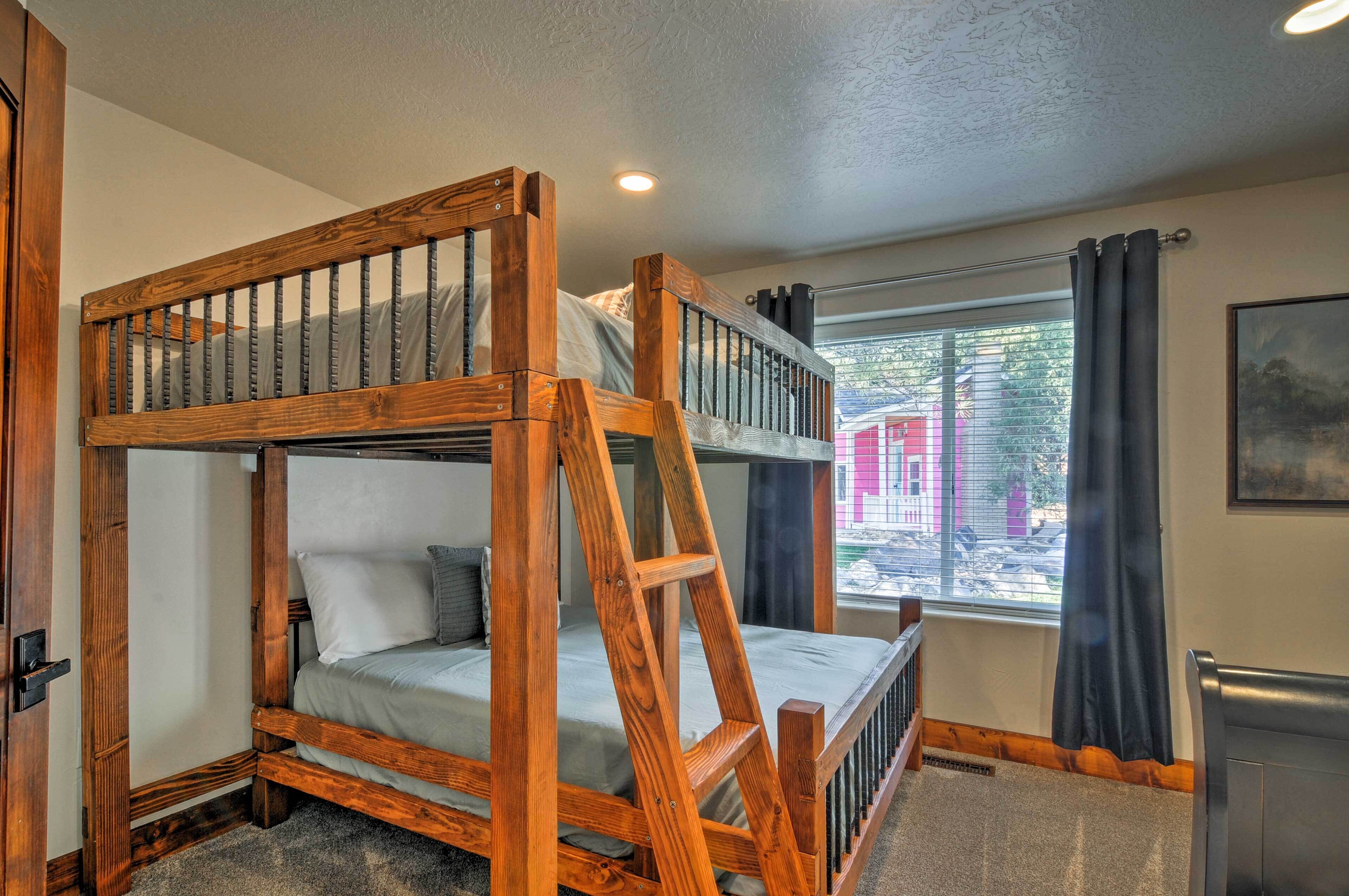 A bunk bed with a wooden frame and a window with curtains.