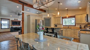 A spacious kitchen with white cabinets, a granite countertop, and a large dining table. - Luxe Home ~ 2 Mi to Bryce Canyon National Park! (Bryce Canyon)