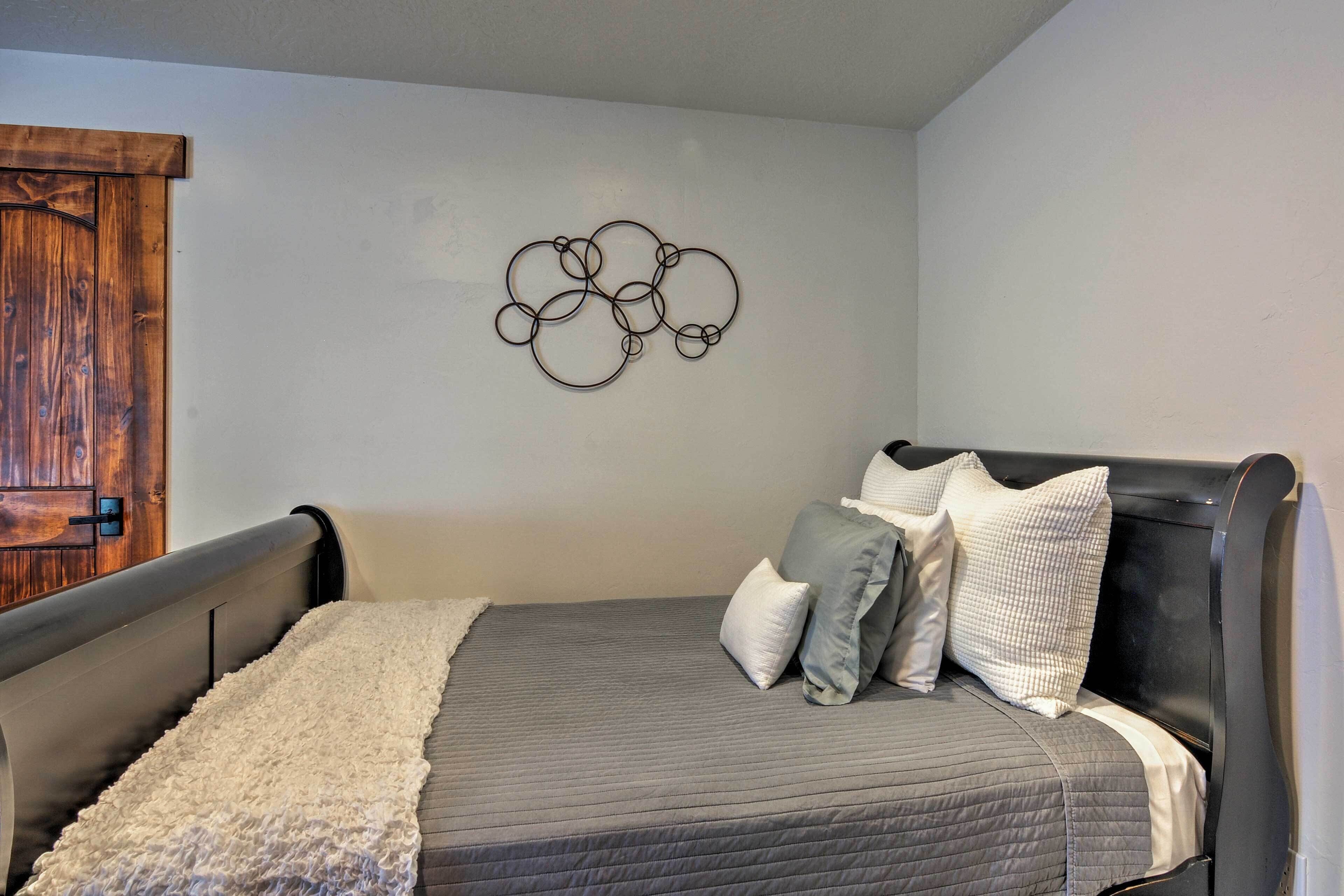 Un dormitorio con cama, almohadas, una obra de arte en la pared y una puerta de madera.