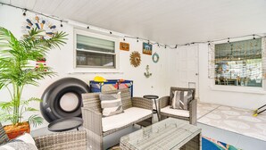 A cozy patio area with wicker furniture, a glass-top table, and a potted plant.
