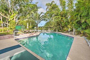 Relax by the serene pool surrounded by lush greenery and lounge chairs.