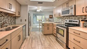 A modern kitchen with wooden cabinets, stainless steel appliances, and a skylight.