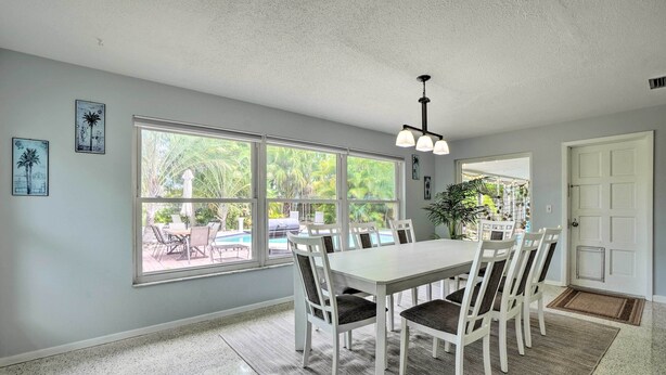 A dining area with a large window, a white table, and chairs.